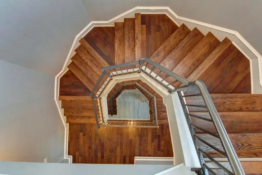 Wooden spiral staircase with metal railing viewed from above.