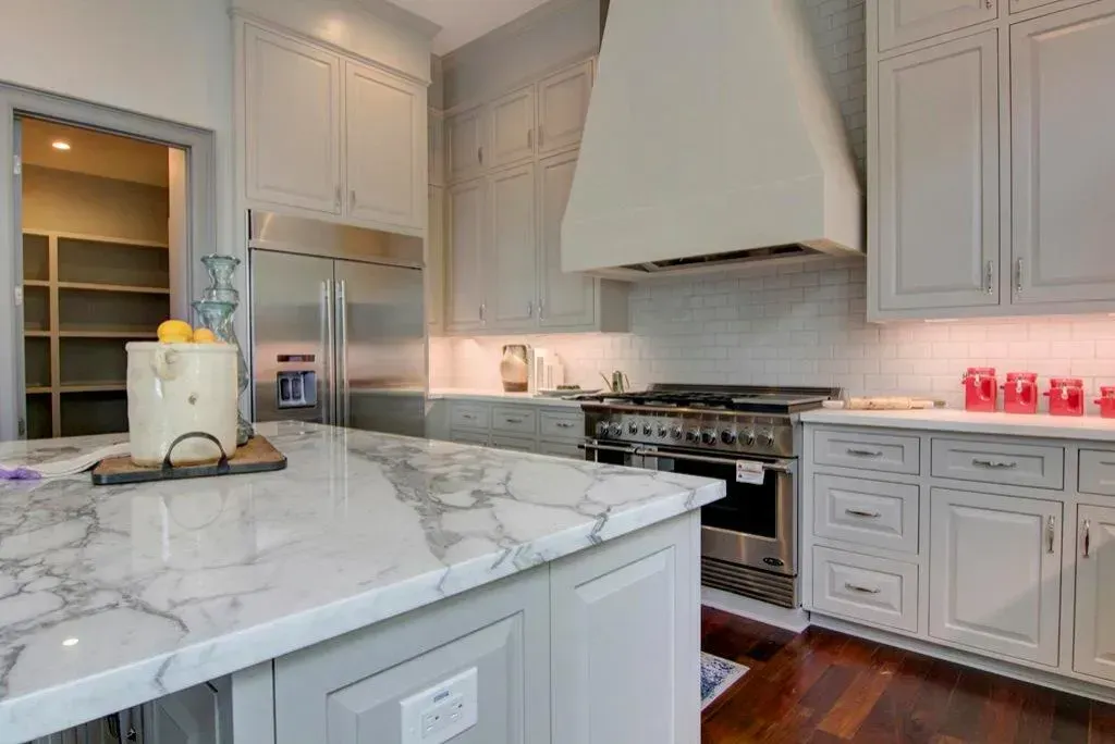 Gray and white kitchen with a marble countertop island and stainless steel appliances.