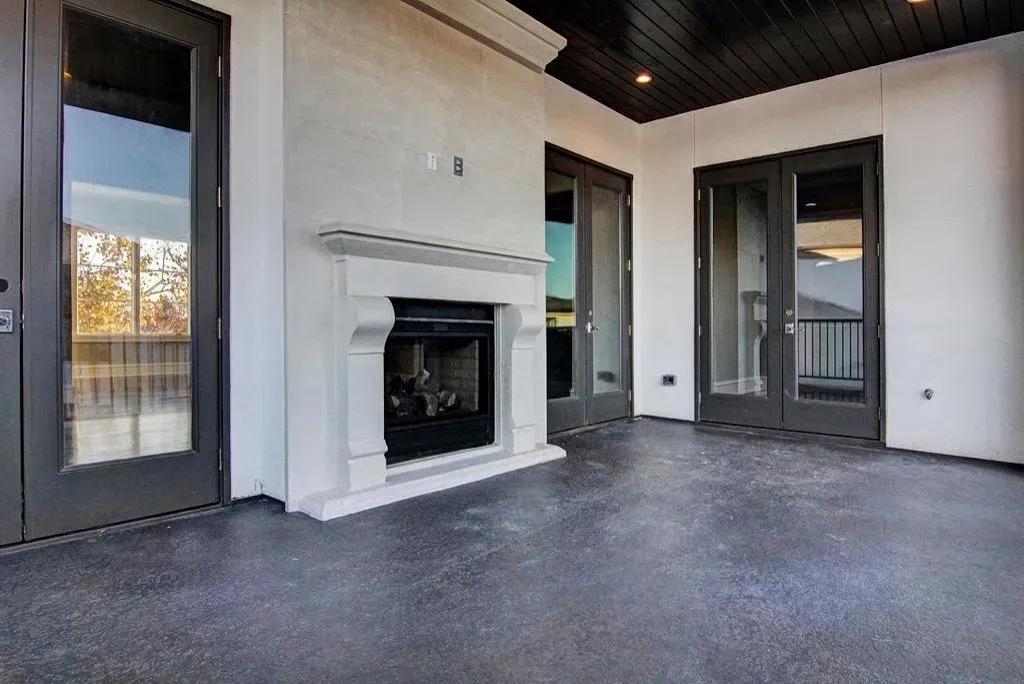 Outdoor patio with a fireplace and black doors.