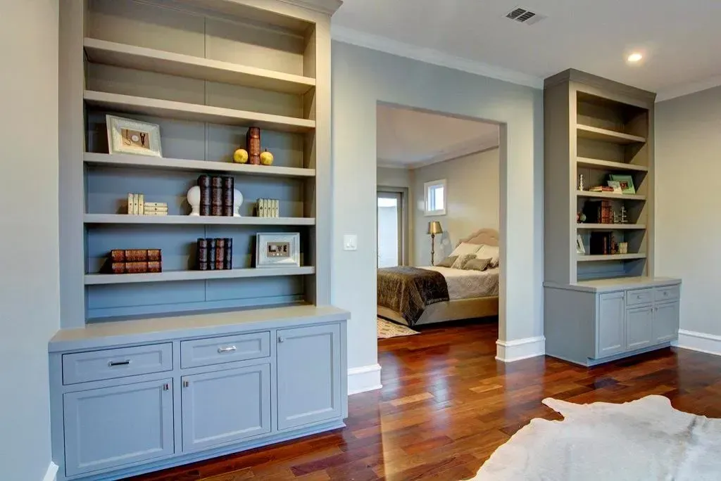 Built-in bookshelves flank a doorway, leading to a bedroom with hardwood floors.