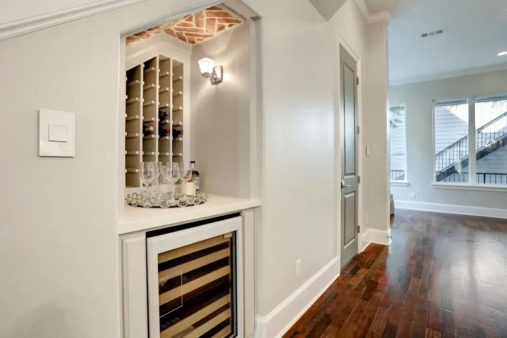 Wine storage niche with brick accent, wine rack, cooler, and barware.