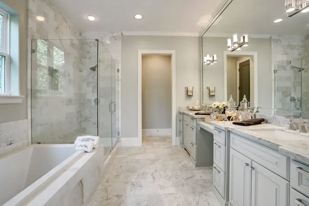 Luxurious modern bathroom with marble floors and walls, a large bathtub, and a glass shower.