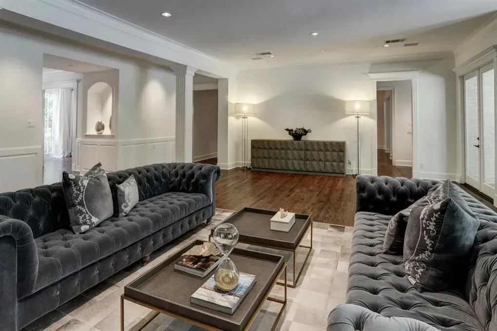 Spacious living room with gray tufted sofas, dark wood coffee tables, and hardwood floors.
