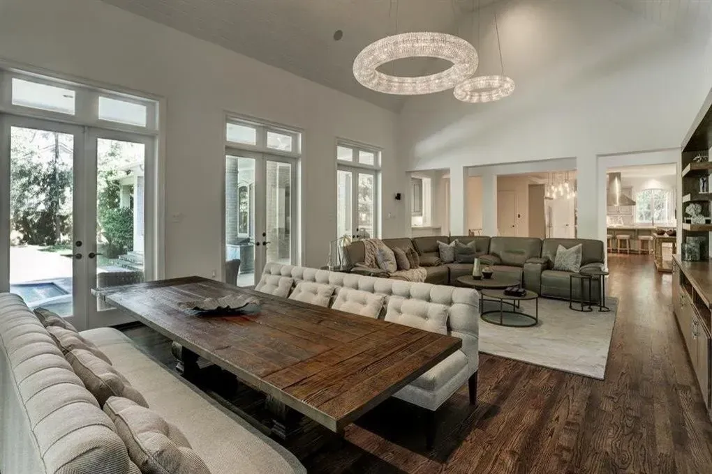 Spacious dining/living room with long wooden table, tufted benches, and light-filled windows.