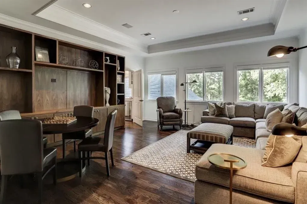 Living room with dark wood built-in shelving, dark wood floors, and a gray sectional sofa.