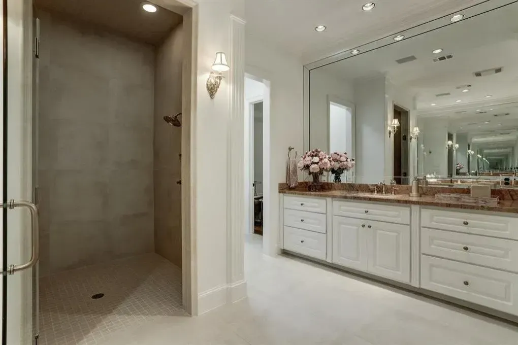 Luxurious white bathroom with shower, vanity, and large mirror.