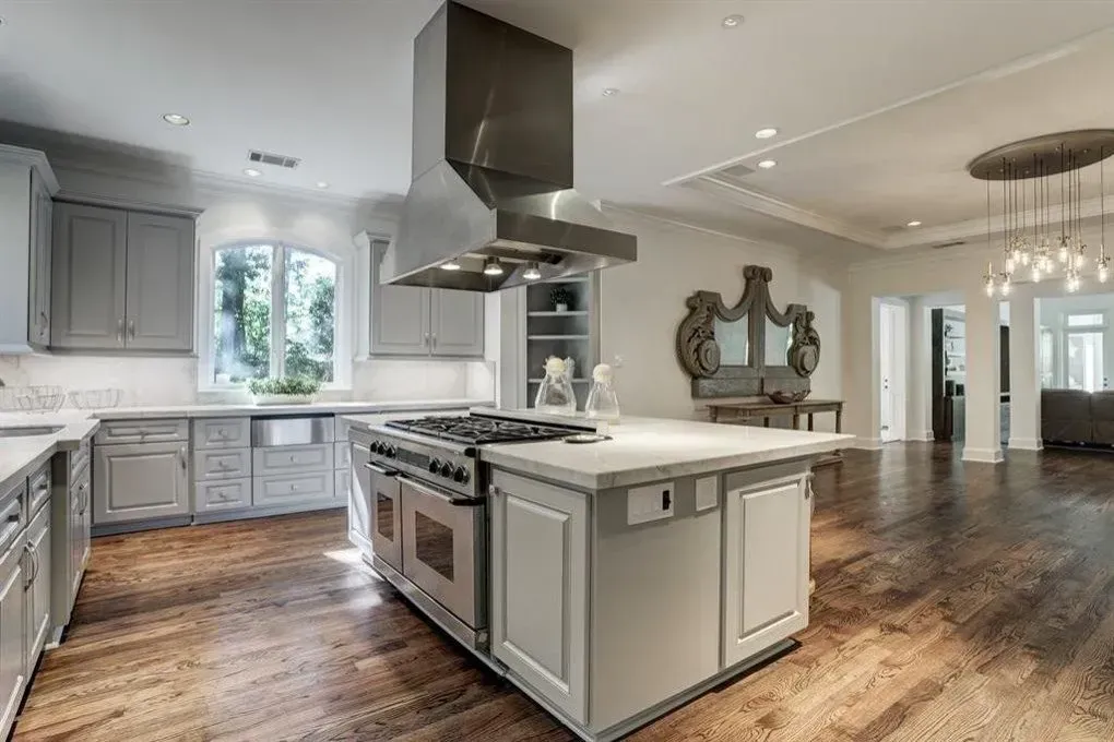 Upscale kitchen with grey cabinets, white countertops, and stainless steel appliances. Hardwood floors.