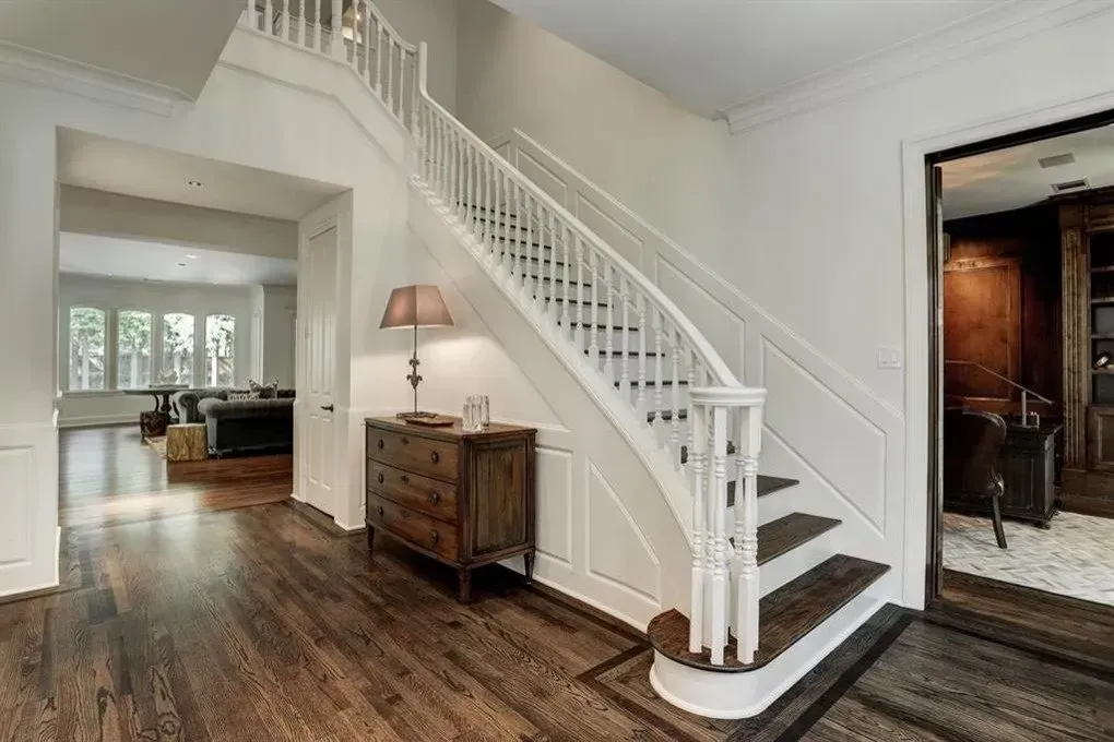 Elegant home entryway with staircase, hardwood floors, and a chest of drawers.