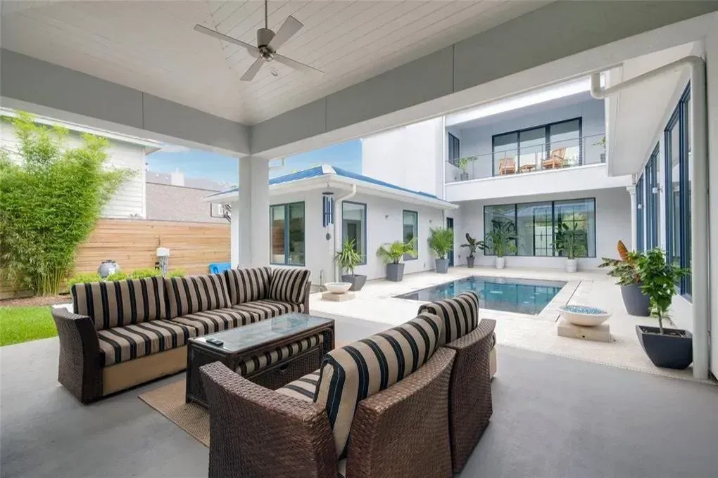 Outdoor patio with seating, pool, and modern house in background.