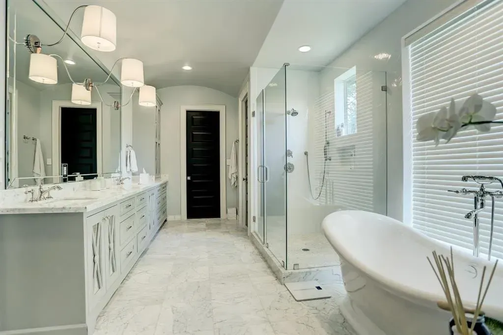 Spacious, modern bathroom with a white freestanding tub, glass shower, and double vanity.