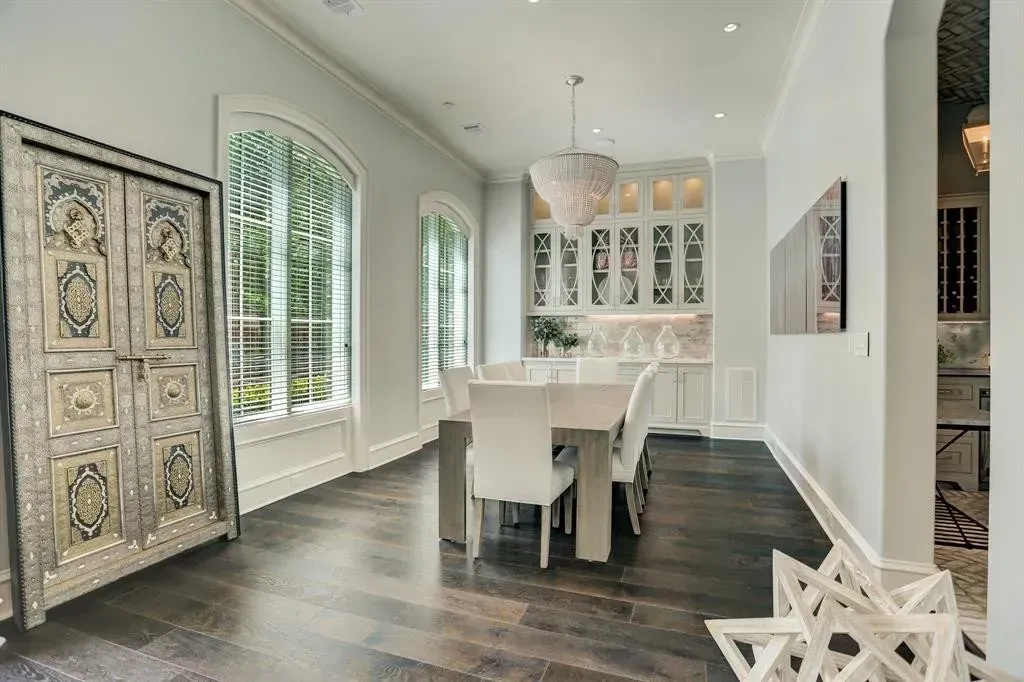 Elegant dining room with dark wood floors, white table, and ornate antique door.