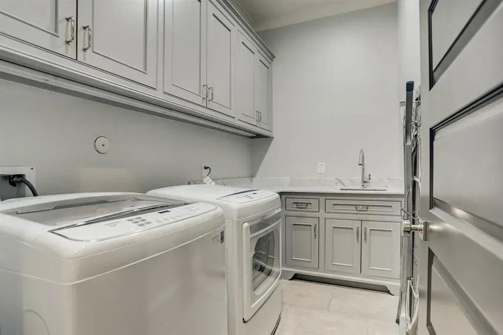 Laundry room with gray cabinets, washer, dryer, and sink.