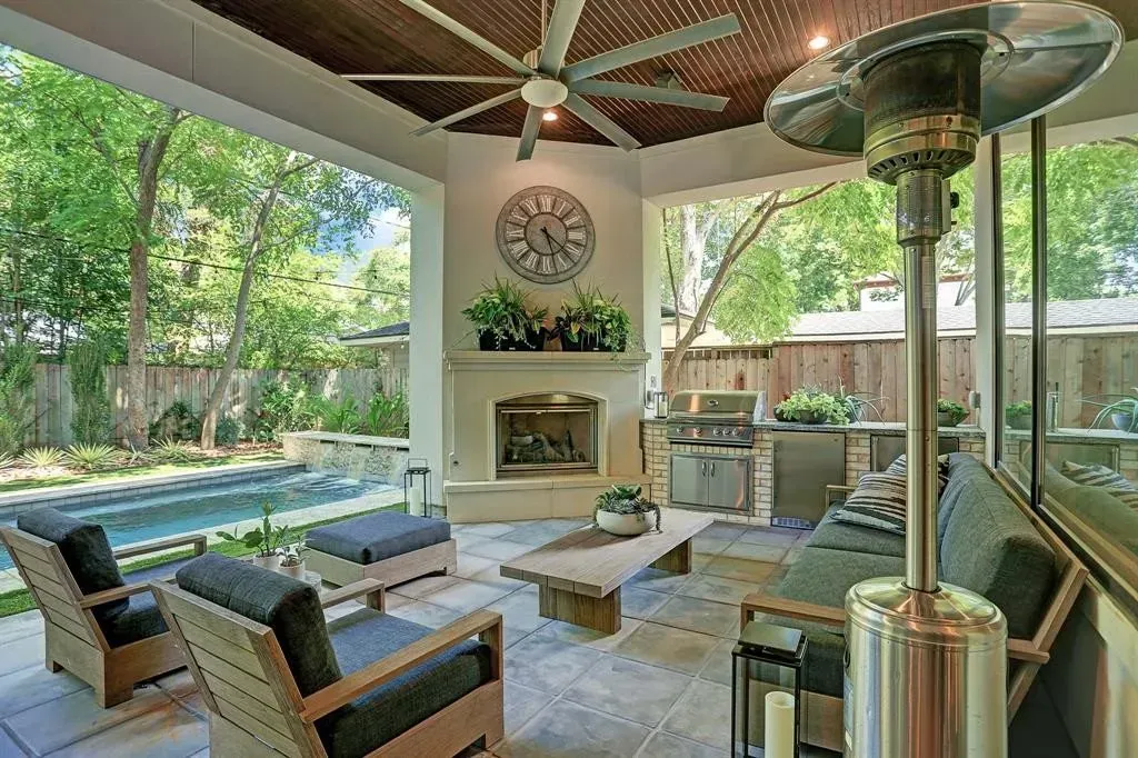 Covered outdoor patio with seating, fireplace, and pool view.