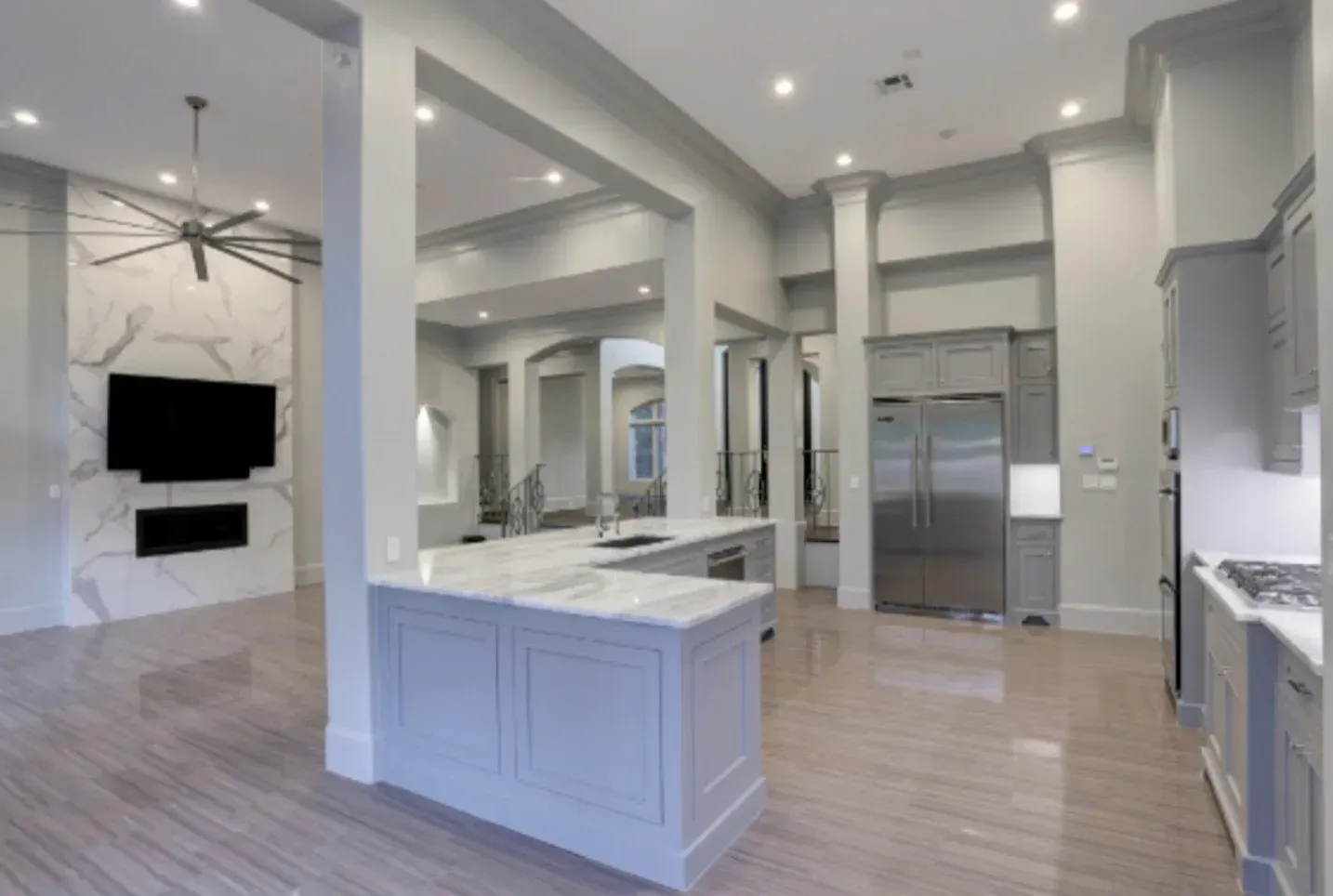 Open-concept kitchen and living area, marble floors, white walls, stainless steel appliances, and island with countertop.