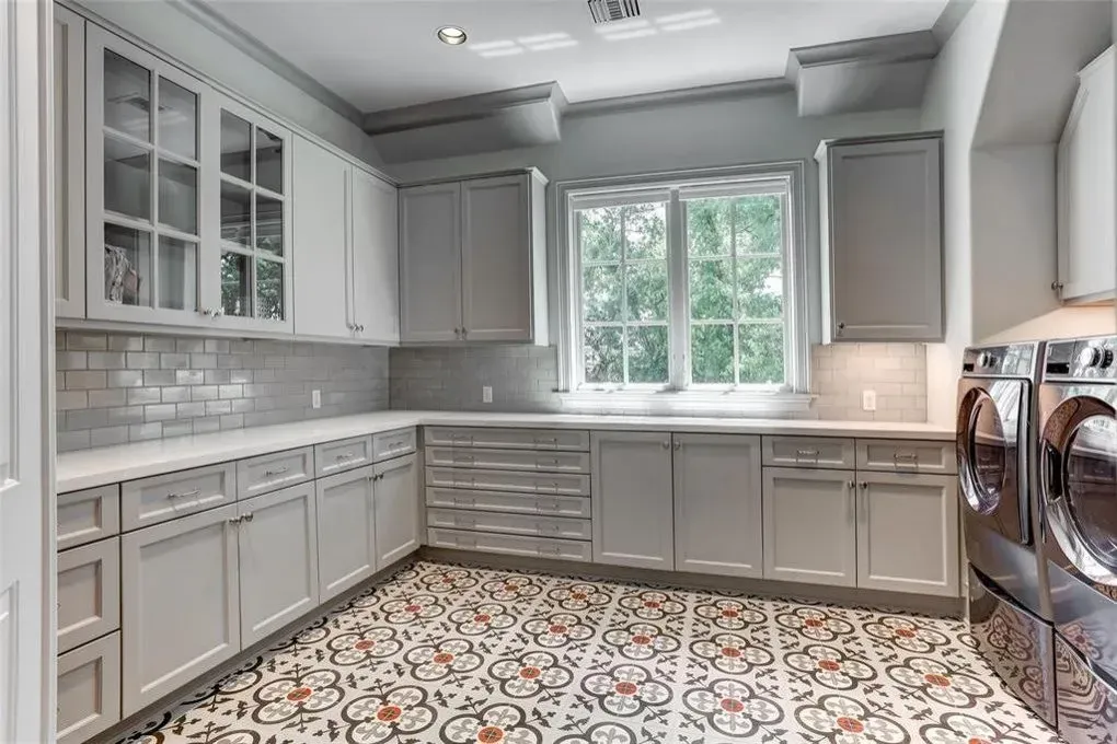 Laundry room with gray cabinets, patterned floor, and window.