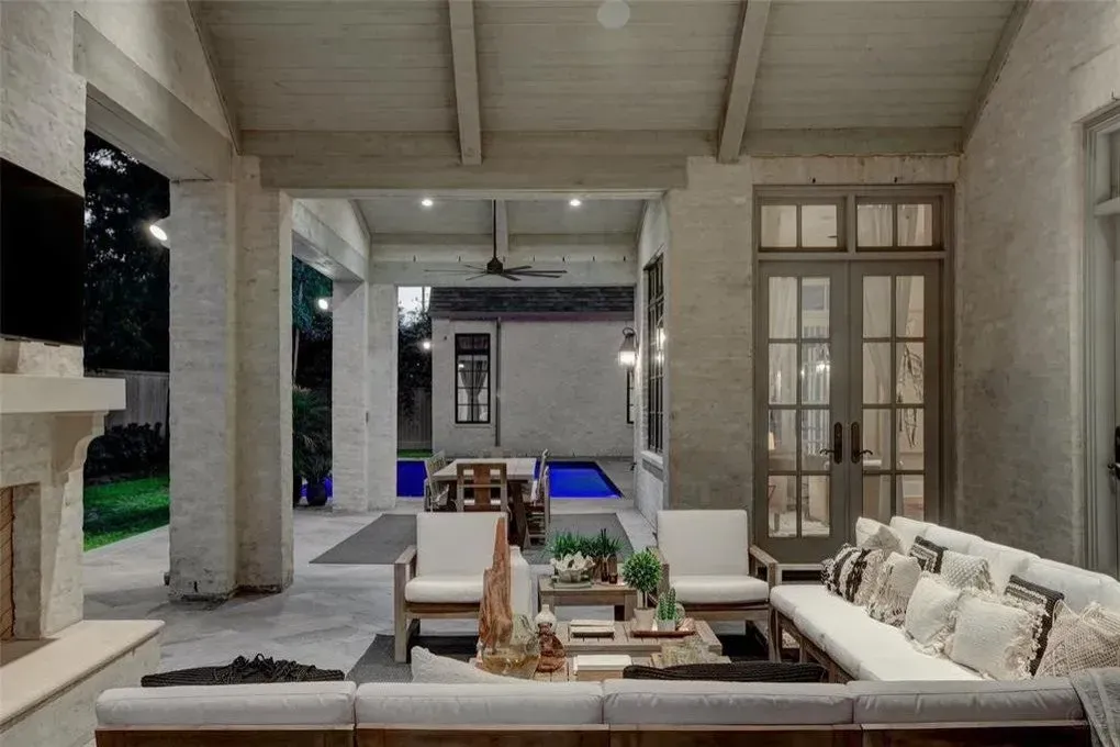 Covered outdoor patio with seating, fireplace, and view of pool and dining area.