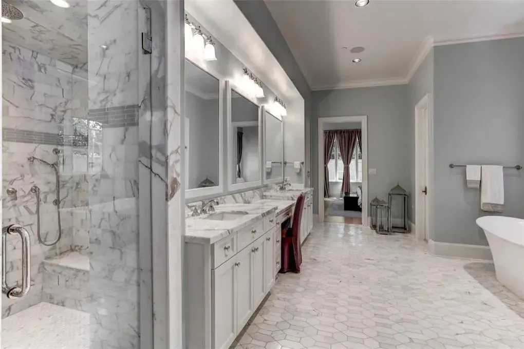 Luxurious bathroom with marble shower, double vanity, bathtub, and blue walls.
