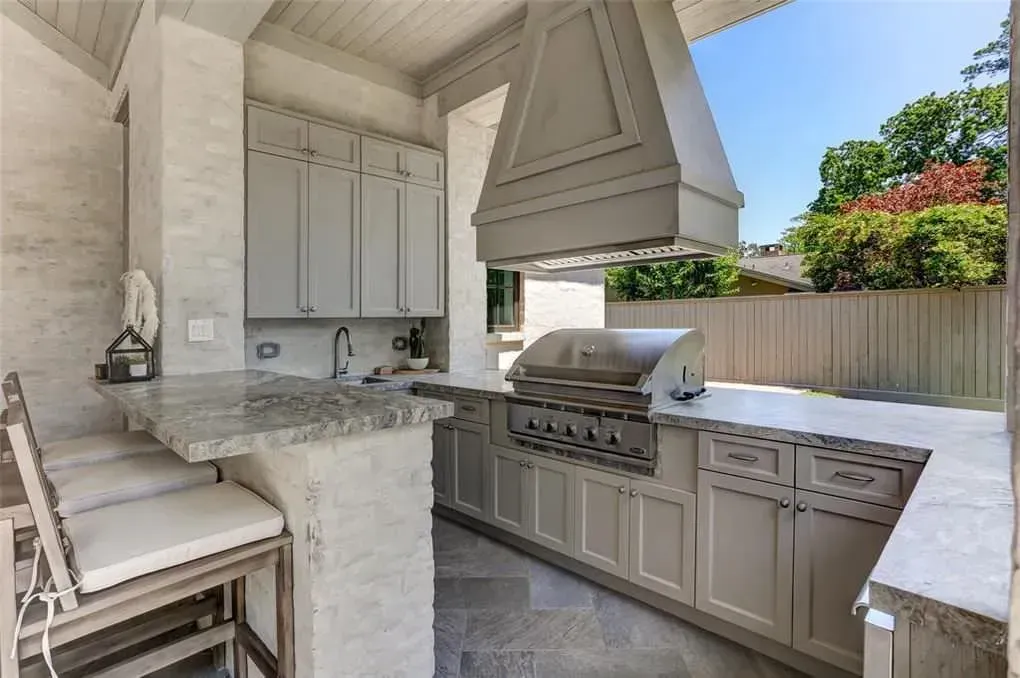 Outdoor kitchen with a grill, cabinets, and a granite countertop.