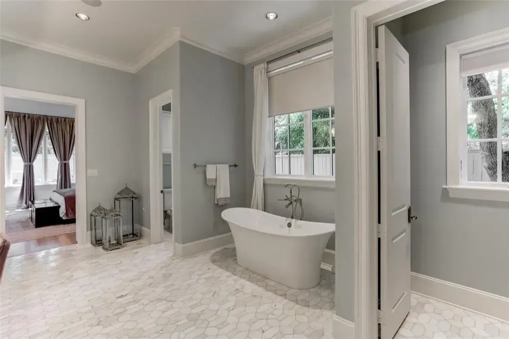 Spacious bathroom with freestanding tub, hexagonal tile floor, and light gray walls.