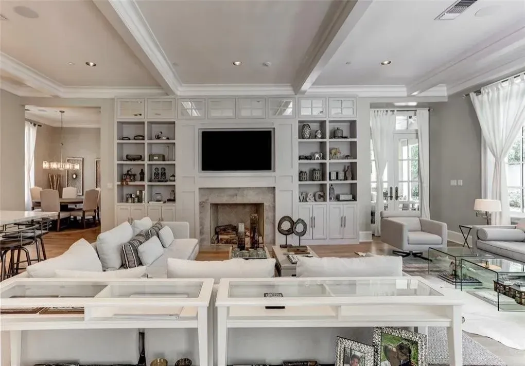 Spacious living room with white built-ins, fireplace, sofa, and glass-top tables.