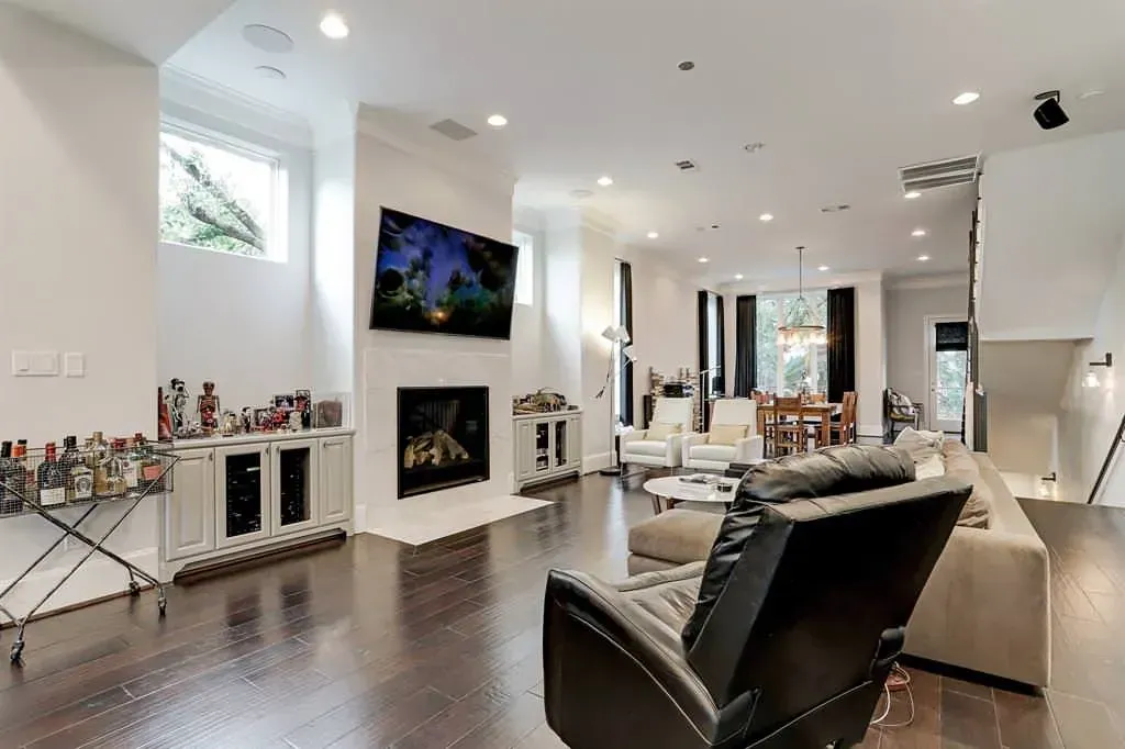 Spacious living room with fireplace, mounted TV, dark wood floor, and multiple seating areas.