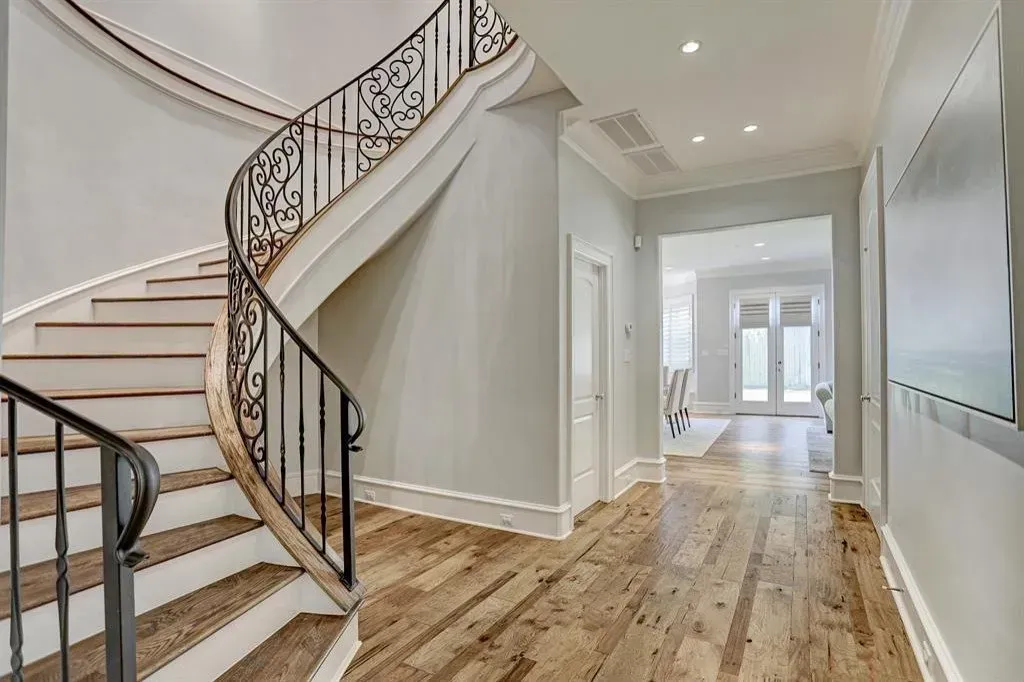 Elegant entry hall with curved staircase and hardwood floor.