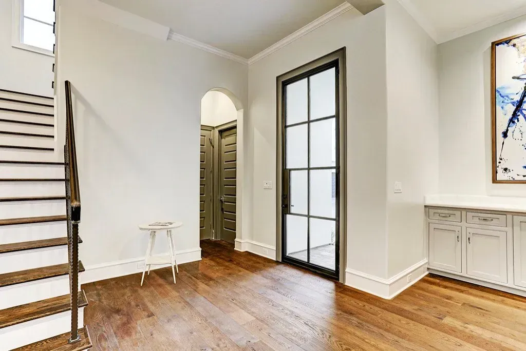 Entryway with hardwood floors, a staircase, and a glass-paneled door.