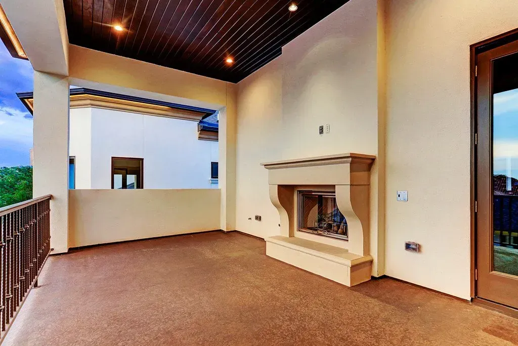 Patio with fireplace, brown flooring, and wooden ceiling. Exterior view with surrounding balcony.