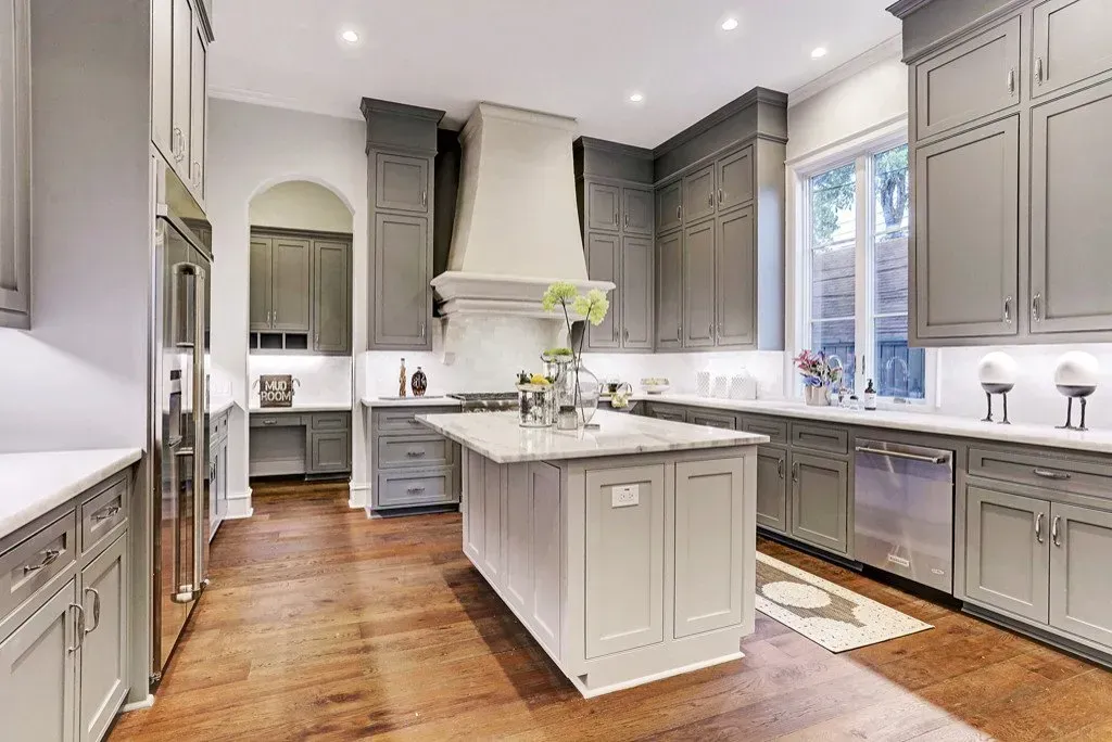 Gray kitchen with marble countertops, stainless steel appliances, and hardwood floors.