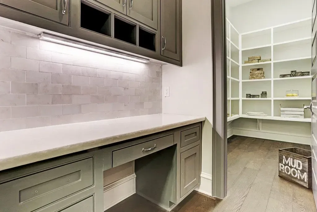 Grey cabinetry with a countertop, under-cabinet lighting, and a pantry with shelves. 