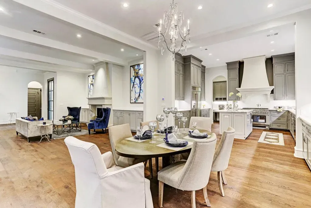 Open-concept kitchen and dining area with gray cabinetry, a chandelier, and hardwood floors.