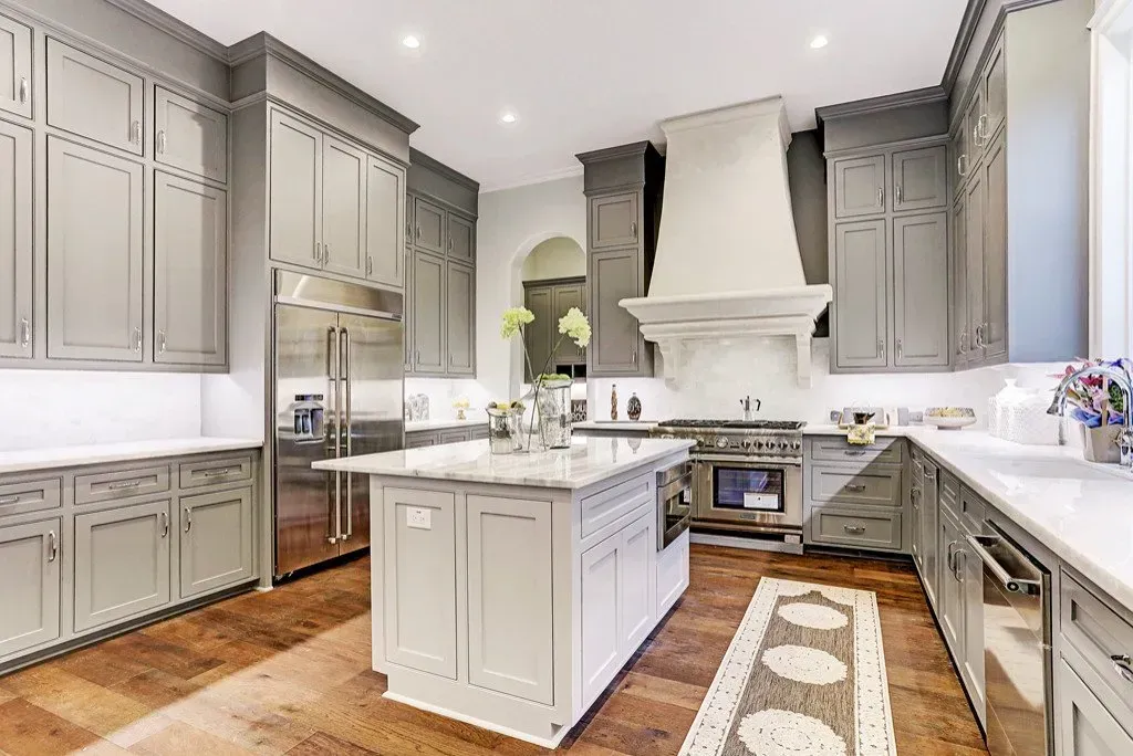 Gray and white kitchen with island, stainless steel appliances, and wood floor.