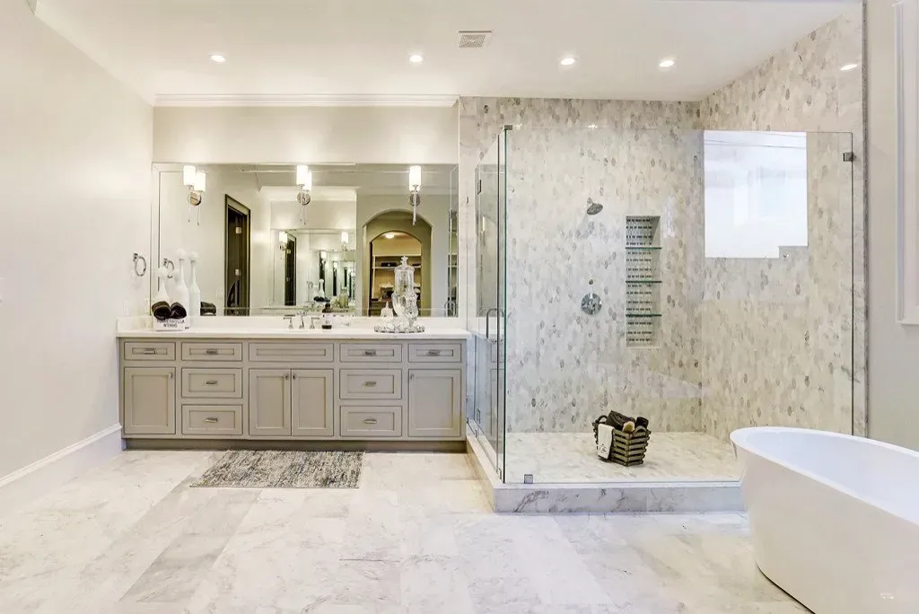 Spacious, modern bathroom with marble tile, glass shower, double vanity, and freestanding tub.