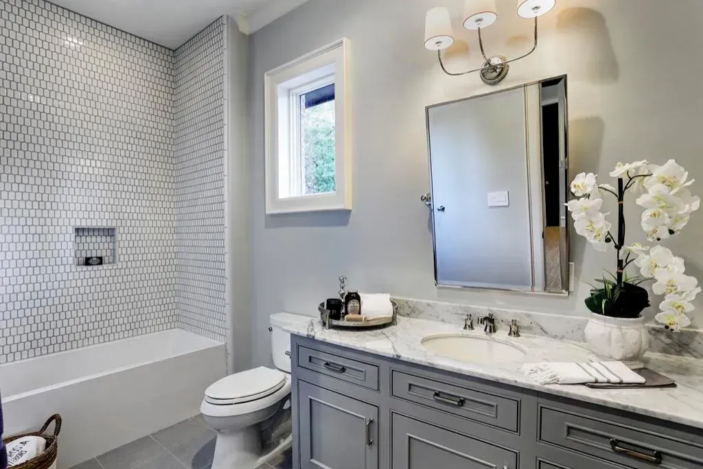 Bathroom with gray vanity, white marble countertop, and patterned tile backsplash.
