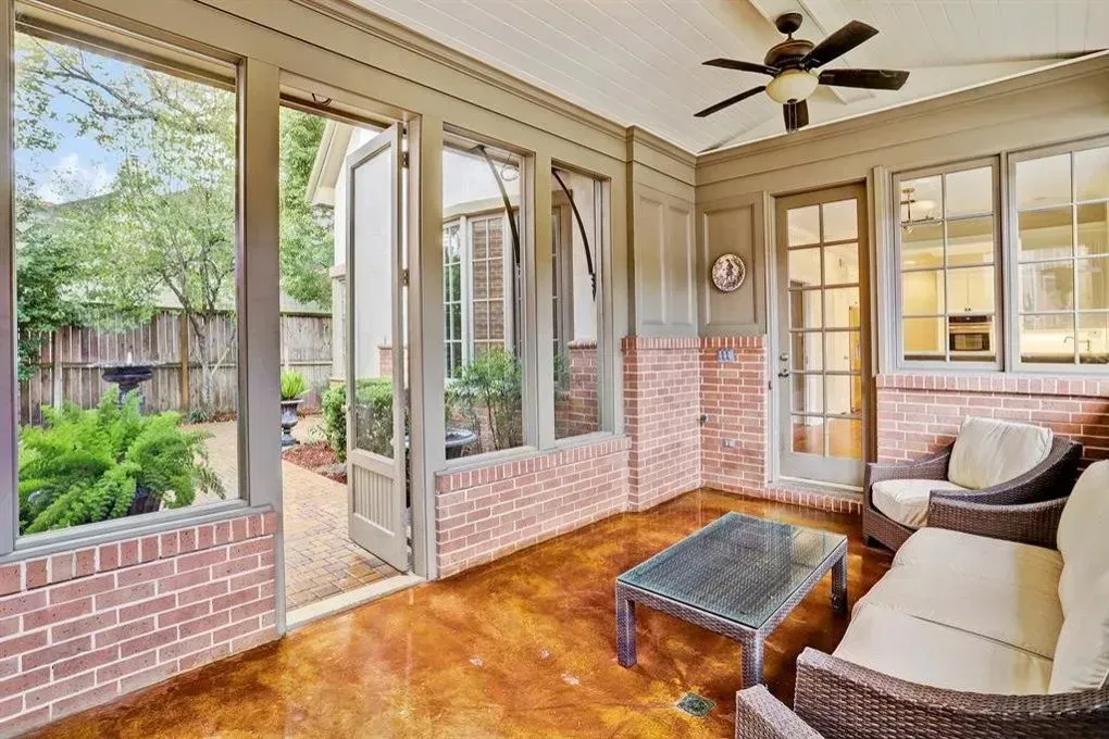 Sunroom with brick walls, open windows to a courtyard, and wicker furniture.