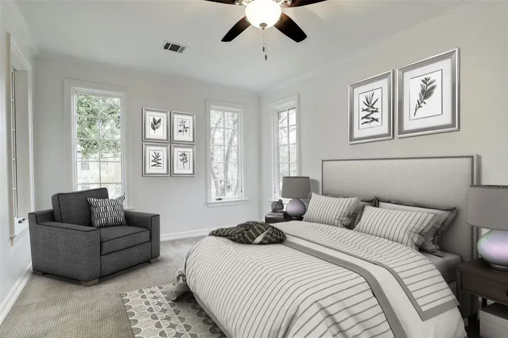 Bedroom with bed, armchair, windows, art, and neutral color scheme.