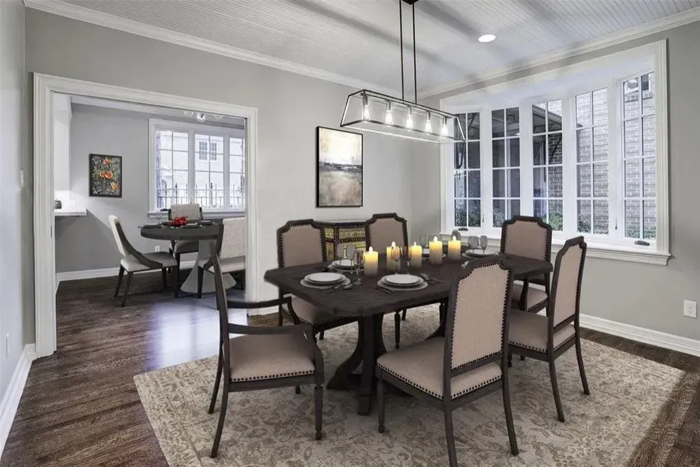Dining room with dark wood table and chairs, rug, candles, and bay window.
