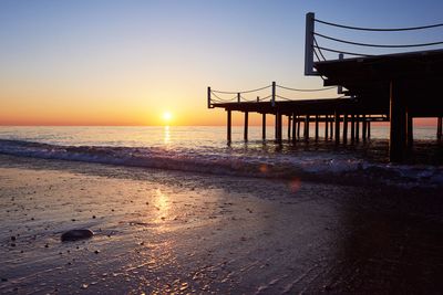 A sunset over the ocean with a pier in the foreground