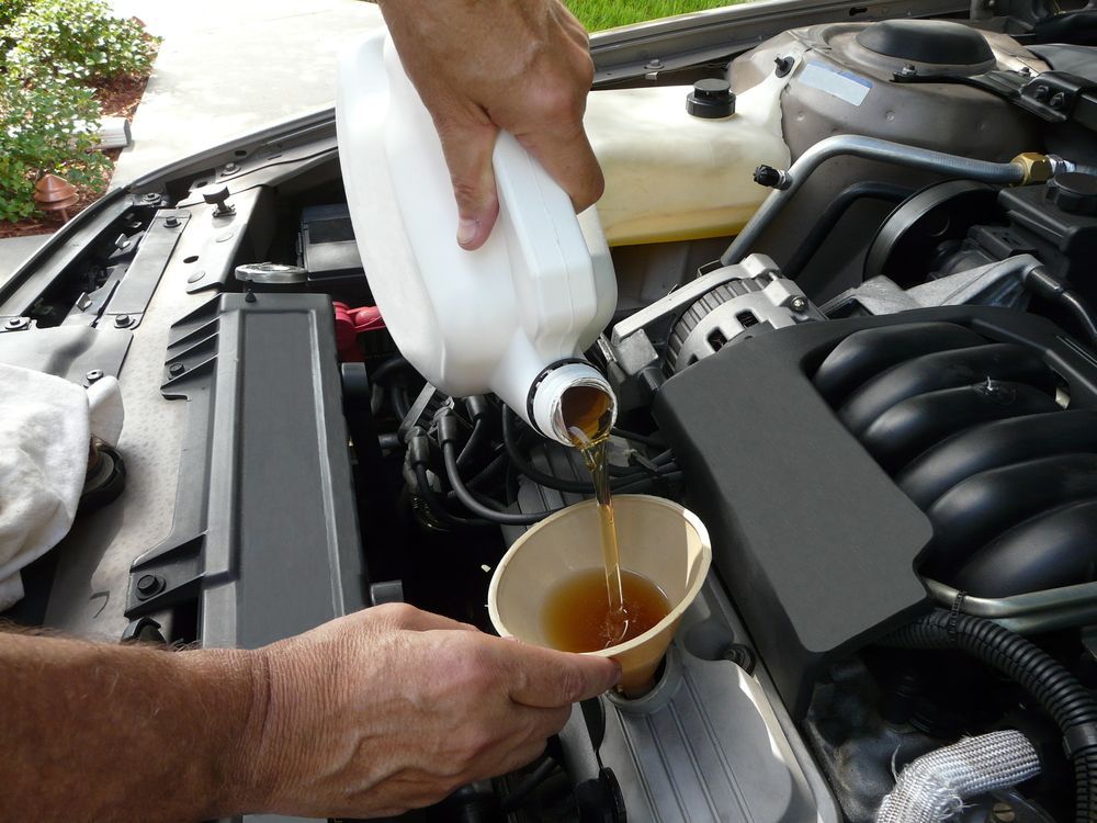 Person Pouring Oil From a Jug Into a Car Engine, Using a Funnel — Mechanical Care in Belconnen, ACT