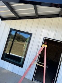 Exterior of building with window and door. Ladder in front.