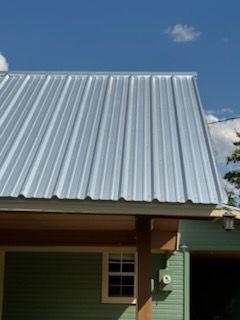 Metal corrugated roof on a green building with a blue sky background.