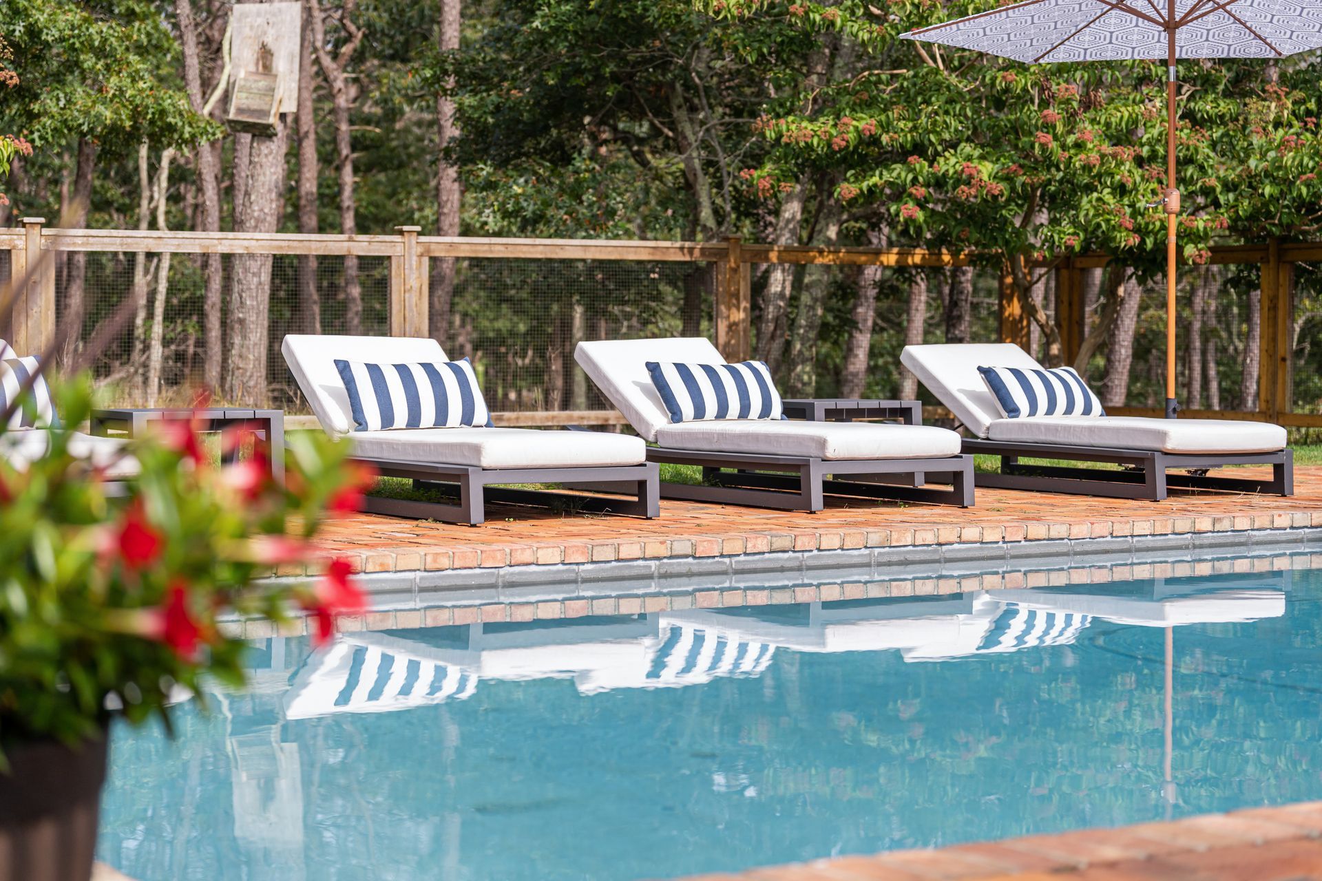 A row of lounge chairs are sitting next to a swimming pool.