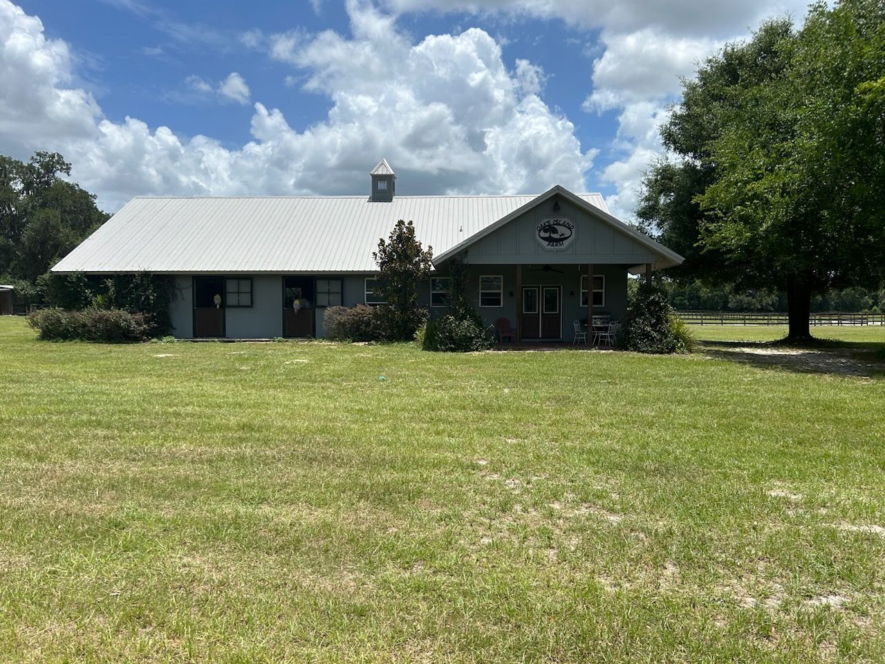A large house is sitting in the middle of a lush green field.