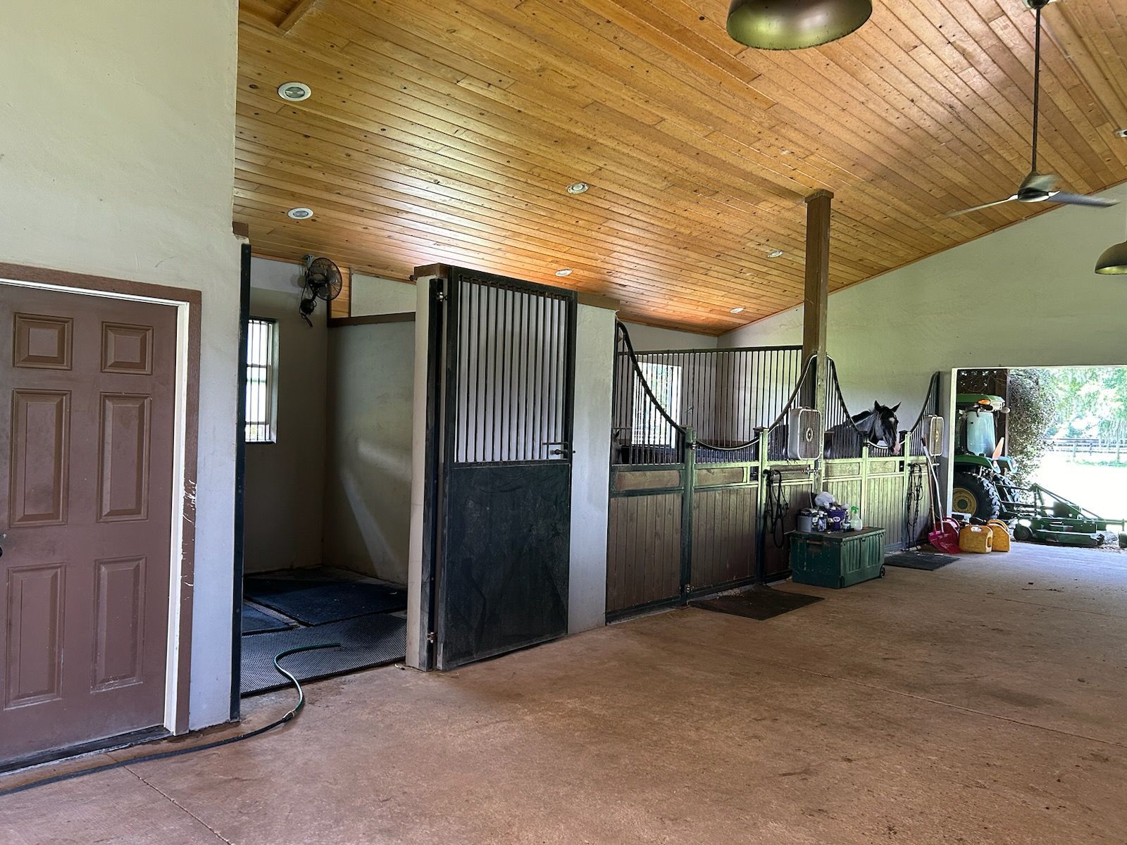 A horse stable with a wooden ceiling and a ceiling fan.