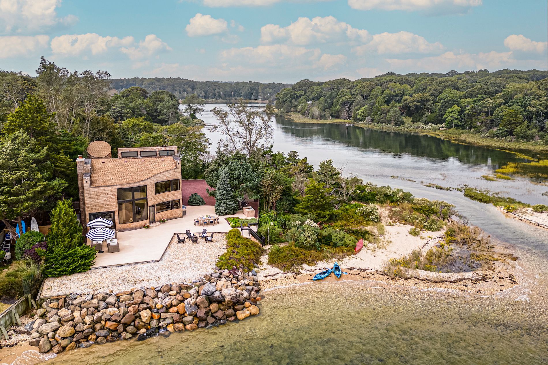 An aerial view of a house on a small island next to a river.