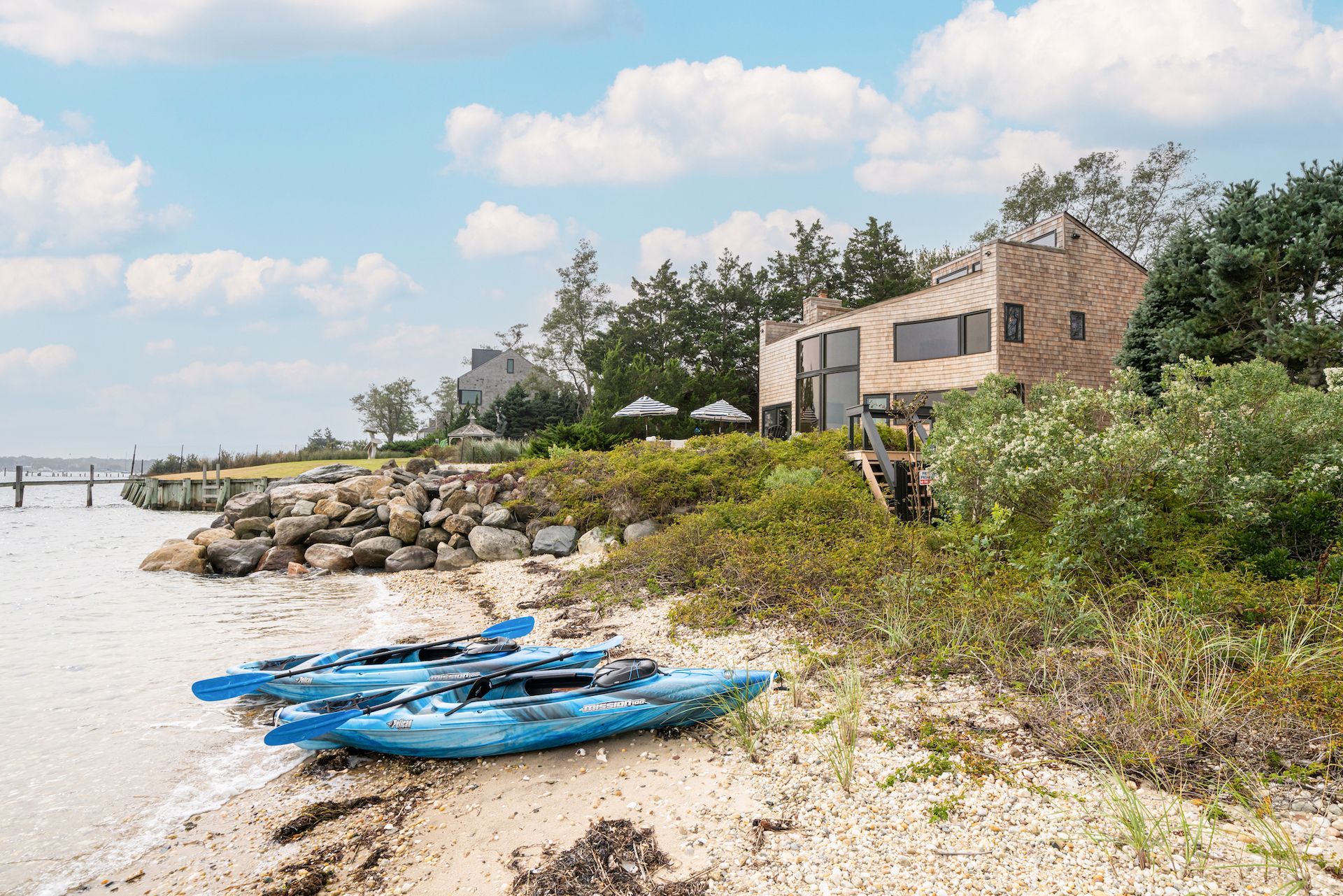 Two blue kayaks are sitting on the beach next to a house.