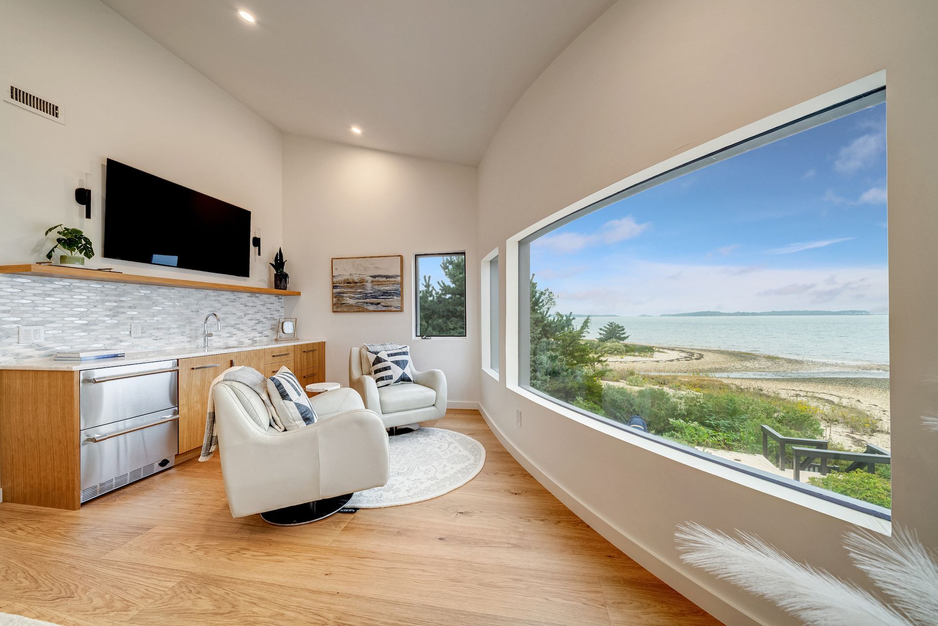 A living room with two chairs and a large window overlooking the ocean.