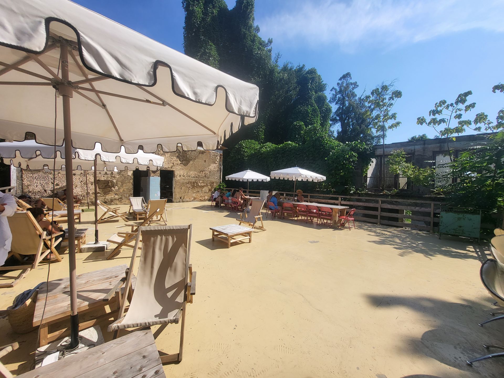 A group of people are sitting under umbrellas in a sandy area