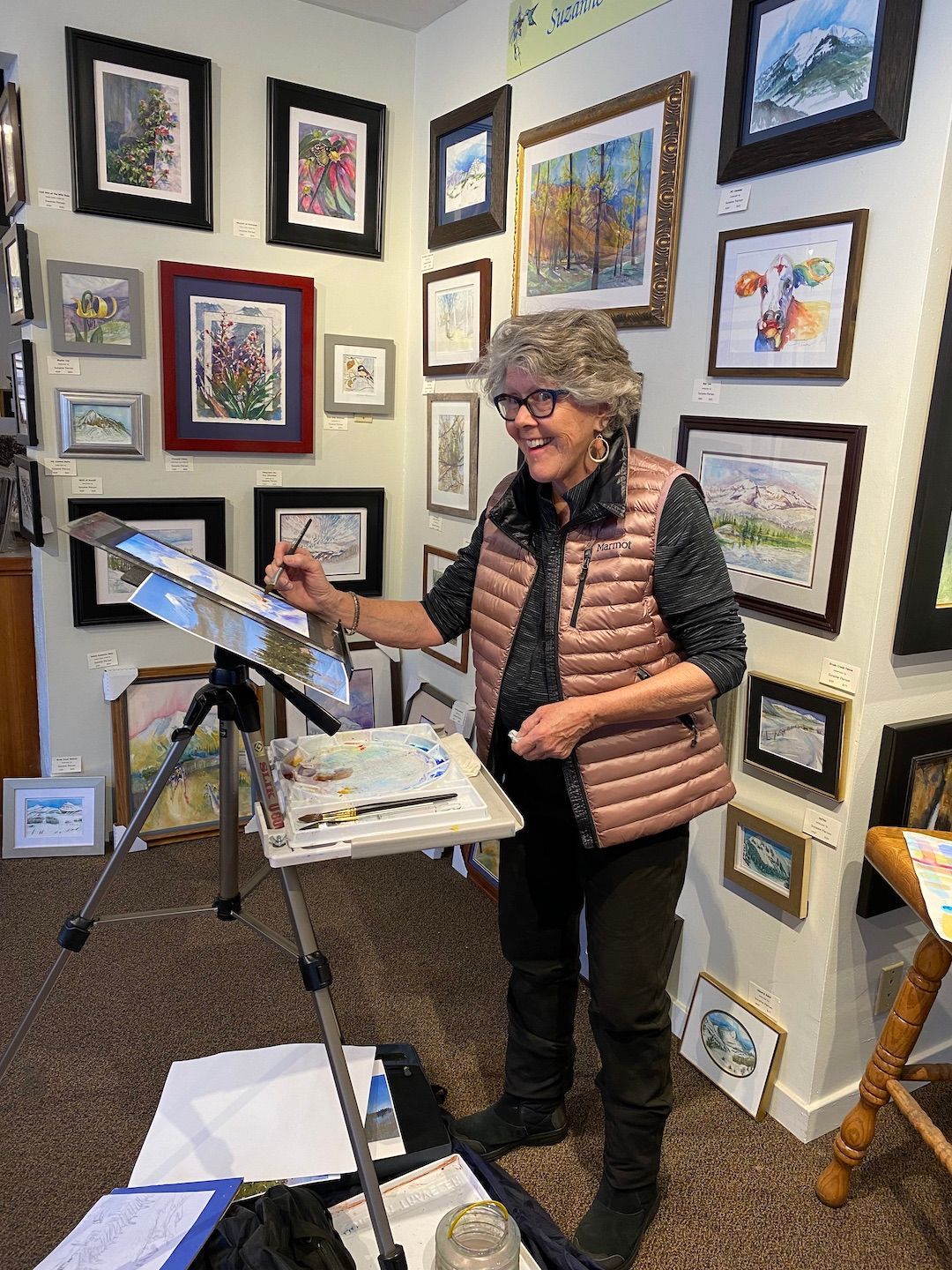A woman is painting a picture on an easel in a room.