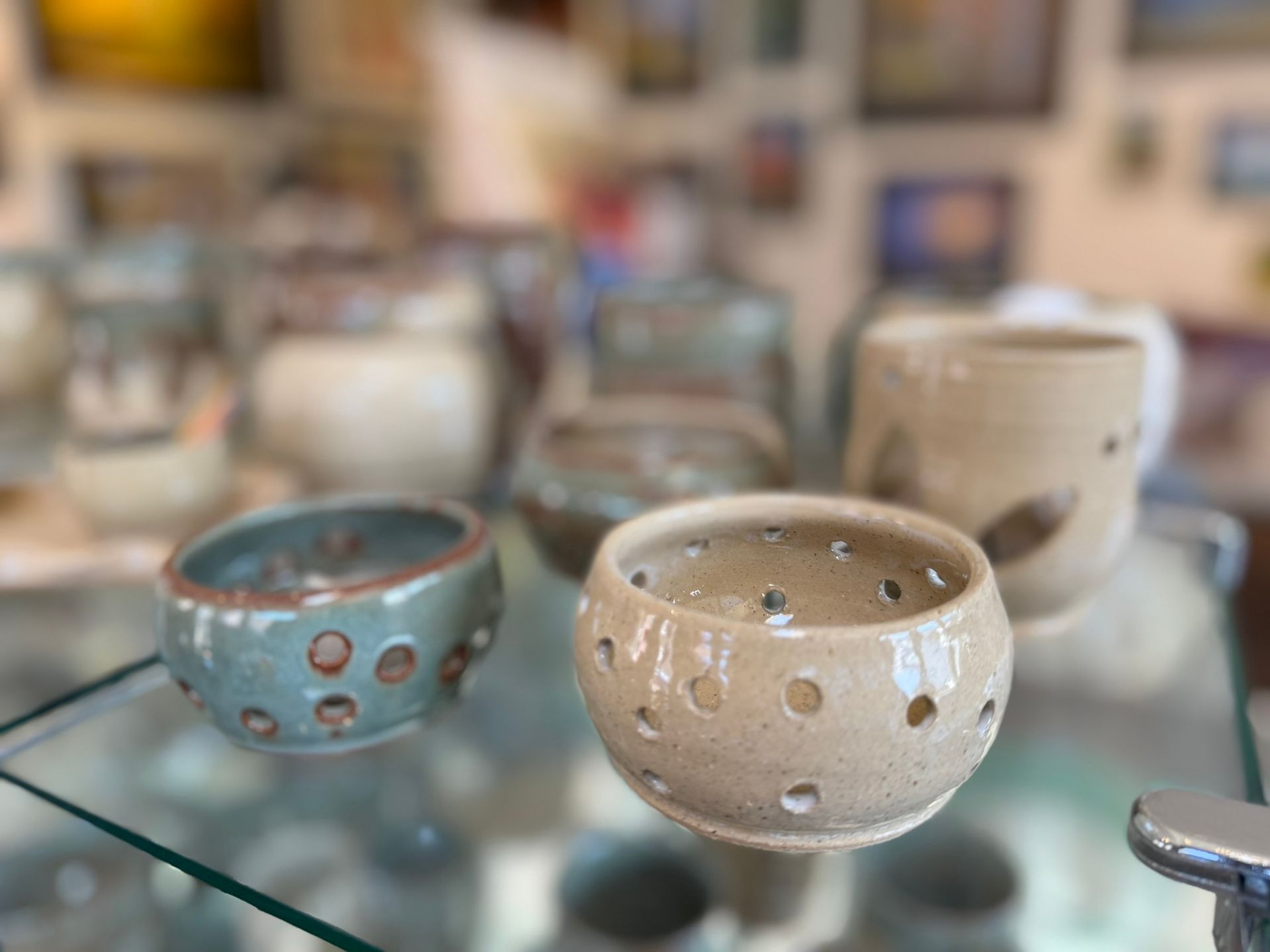 A display of ceramic bowls on a glass shelf in a store.